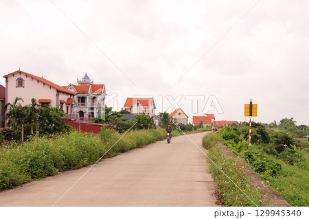 rural road in vietnam with people riding bicycles and motorbikes rural road in vietnam with people riding bicycles and motorbikes 129945340