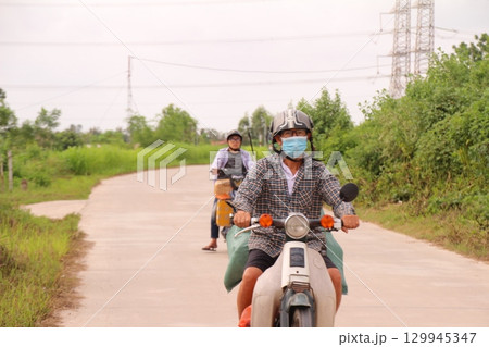 rural road in vietnam with people riding bicycles and motorbikes 129945347