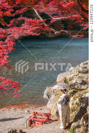 woman in kimono and umbrella by red maple tree in autumn, Arashiyama woman in kimono and umbrella by red maple tree in autumn, Arashiyama 129947228