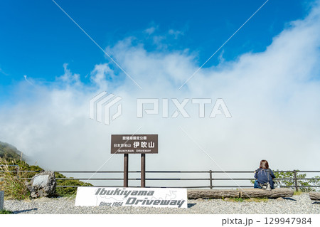 岐阜県関ケ原町　伊吹山ドライブウェイ駐車場からの下界を眺める所にある看板と犬を抱えた女性 129947984