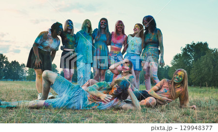 Young people covered in colorful powder celebrating holi festival, posing and enjoying in the park 129948377