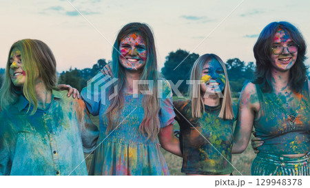 Four school friends joyfully embrace each other covered in vibrant holi powder paint Four school friends joyfully embrace each other covered in vibrant holi powder paint 129948378