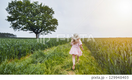 Barefoot child running across verdant meadow near oak tree, experiencing summer joy and natural freedom under bright sunlight Barefoot child running across verdant meadow near oak tree, experiencing summer joy and natural freedom under bright sunlight 129948403