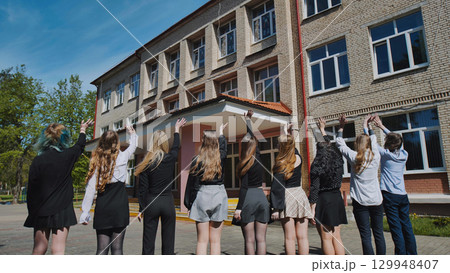Happy students waving goodbye to their school on the last day, marking the start of summer vacation 129948407