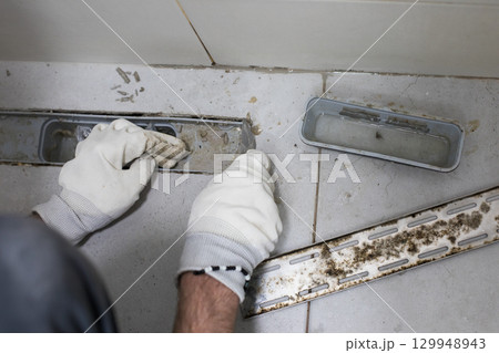 Dirty messy sewer hole, bathroom drain and worker hands 129948943