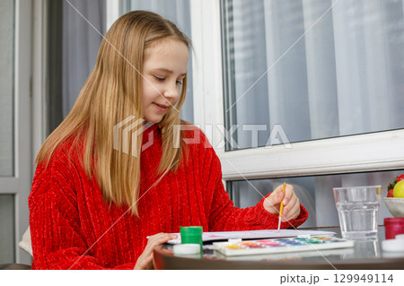 Happy child painting with bright colors. Young girl at home, hobby and leisure 129949114