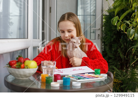 Pretty young girl painting. Child and colorful paints and kitten at home. Childhood Pretty young girl painting. Child and colorful paints and kitten at home. Childhood 129949115