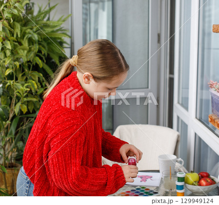 Pretty young girl closing a bottle of paint for drawing 129949124