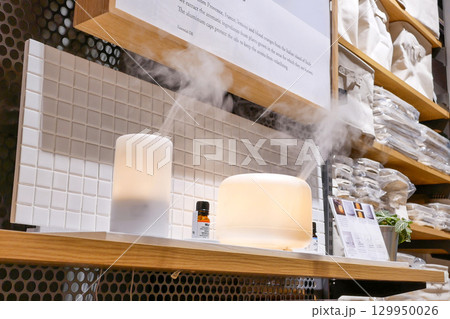 In a cozy retail setting, two essential oil diffusers release gentle streams of mist, creating a calming atmosphere. In a cozy retail setting, two essential oil diffusers release gentle streams of mist, creating a calming atmosphere. 129950026