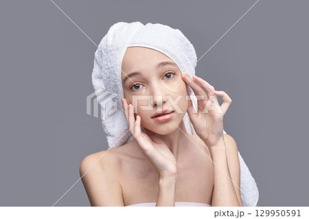 Young caucasian female with towel turban applying eye patches for skincare Young caucasian female with towel turban applying eye patches for skincare 129950591