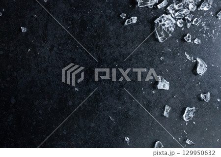Shattered glass on dark surface with broken pieces and textured background 129950632