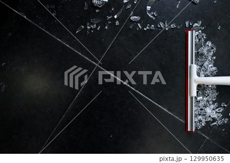 Broken glass cleanup on black tile floor with white and red broom Broken glass cleanup on black tile floor with white and red broom 129950635