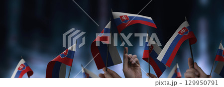 Slovakia flags in their hands on a blurred urban background 129950791
