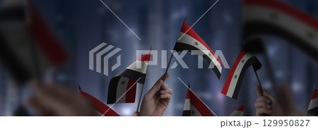 Syria flags in their hands on a blurred urban background 129950827