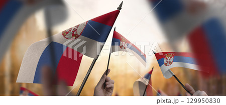Serbia flags in their hands on a blurred urban background Serbia flags in their hands on a blurred urban background 129950830
