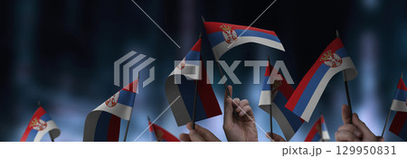 Serbia flags in their hands on a blurred urban background Serbia flags in their hands on a blurred urban background 129950831