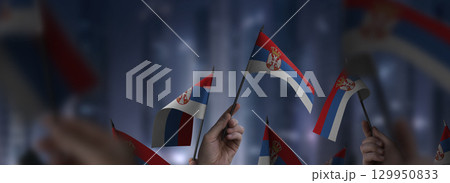 Serbia flags in their hands on a blurred urban background Serbia flags in their hands on a blurred urban background 129950833
