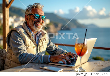 Smiling senior man using laptop 129951243