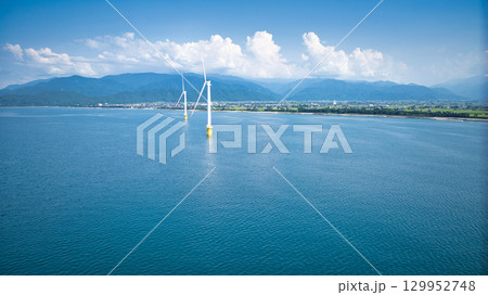 8月の終わりの富山県下新川海岸と洋上風力発電風車 129952748