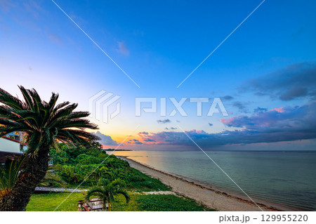 石垣島の夕焼けに染まる砂浜とヤシの木のリゾート風景 石垣島の夕焼けに染まる砂浜とヤシの木のリゾート風景 129955220
