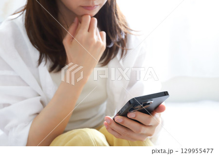 スマートフォンを見て落ち込む女性 スマートフォンを見て落ち込む女性 129955477