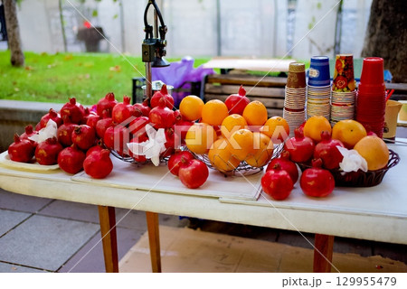 Fresh fruits including pomegranates and oranges with a table press juicer machine in a street in Tbilisi, Georgia Fresh fruits including pomegranates and oranges with a table press juicer machine in a street in Tbilisi, Georgia 129955479