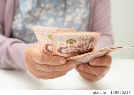Retired elderly woman counting coins money and worry about monthly expenses and treatment fee payment. 129956237