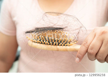 Asian woman have problem with long hair loss attach to comb brush. 129956238