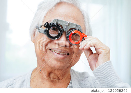 Optometrist checking Asian elderly woman ophthalmic vision eye test and using optical trial frame. Optometrist checking Asian elderly woman ophthalmic vision eye test and using optical trial frame. 129956243