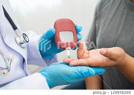 Doctor check diabetes from finger blood sugar level with digital glucose monitor measure and test stripe. 129956269
