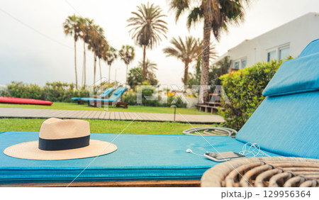 A beach chair with a straw hat on it and a cell phone on it A beach chair with a straw hat on it and a cell phone on it 129956364