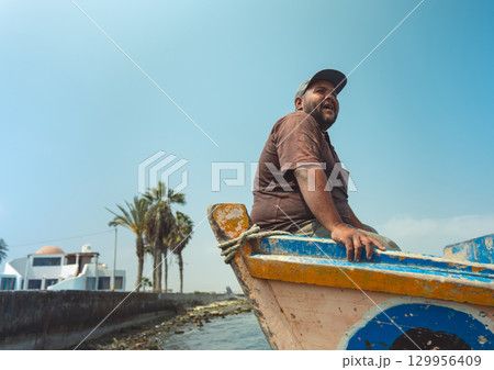 A man is sitting in a boat on a body of water, fisherman in his boat, real job A man is sitting in a boat on a body of water, fisherman in his boat, real job 129956409