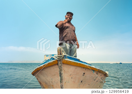 A man is standing on a boat with a woman painted on the side, fisherman in his boat, real job A man is standing on a boat with a woman painted on the side, fisherman in his boat, real job 129956419