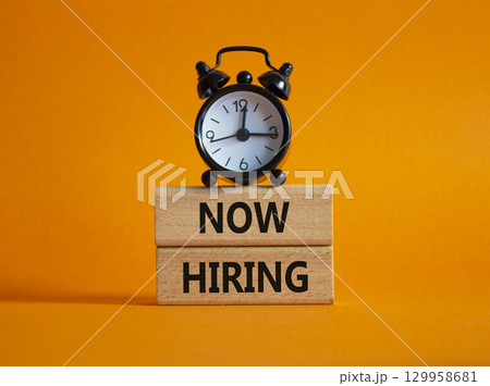 Now Hiring symbol. Wooden blocks with words Now Hiring. Beautiful orange background with alarm clock. Business and Now Hiring concept. Copy space. Now Hiring symbol. Wooden blocks with words Now Hiring. Beautiful orange background with alarm clock. Business and Now Hiring concept. Copy space. 129958681