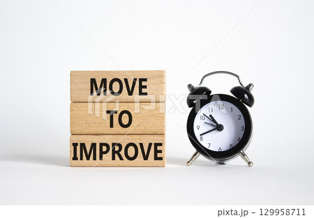 Move to Improve symbol. Concept words Move to Improve on wooden blocks. Beautiful white background with alarm clock. Business and Move to Improve concept. Copy space. 129958711