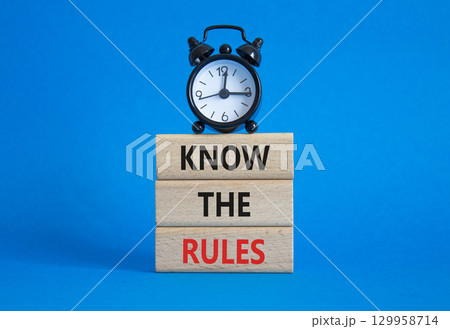 Know the rules symbol. Wooden blocks with words Know the rules. Beautiful blue background with alarm clock. Business and Know the rules concept. Copy space. 129958714
