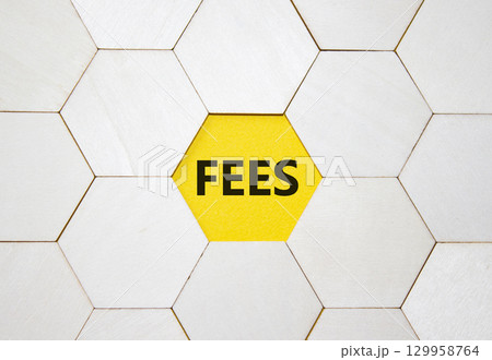 Fees symbol. Concept word Fees on wooden comb puzzle. Beautiful yellow background. Business and Fees concept. Copy space. 129958764