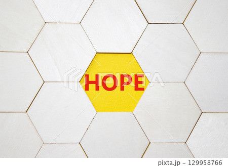 Hope symbol. Concept word Hope on wooden comb puzzle. Beautiful yellow background. Business and Hope concept. Copy space. Hope symbol. Concept word Hope on wooden comb puzzle. Beautiful yellow background. Business and Hope concept. Copy space. 129958766