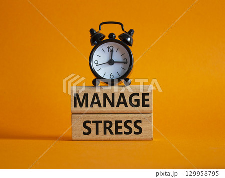 Manage stress symbol. Concept word Manage stress on wooden blocks. Beautiful orange background with alarm clock. Business and Manage stress concept. Copy space 129958795