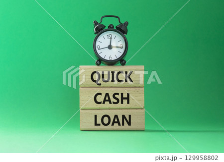 Quick Cash Loan symbol. Concept words Quick Cash Loan on wooden blocks. Beautiful green background with alarm clock. Business and Quick Cash Loan concept. Copy space. 129958802
