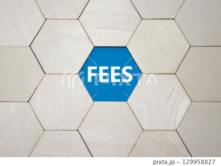 Fees symbol. Concept word Fees on wooden comb puzzle. Beautiful blue background. Business and Fees concept. Copy space. 129958827