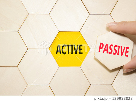 Active or Passive symbol. Concept word Active or Passive on wooden comb puzzle. Businessman hand. Beautiful yellow background. Business and Active or Passive concept. Copy space 129958828