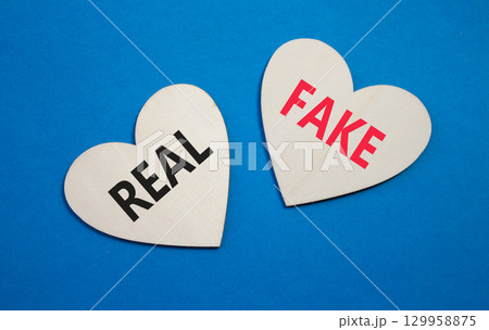 Real or Fake symbol. Concept word Real or Fake on wooden hearts. Beautiful blue background. Business and Real or Fake concept. Copy space Real or Fake symbol. Concept word Real or Fake on wooden hearts. Beautiful blue background. Business and Real or Fake concept. Copy space 129958875