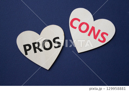 Pros vs Cons symbol. Concept word Pros vs Cons on wooden hearts. Beautiful deep blue background. Business and Pros vs Cons concept. Copy space Pros vs Cons symbol. Concept word Pros vs Cons on wooden hearts. Beautiful deep blue background. Business and Pros vs Cons concept. Copy space 129958881