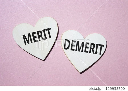 Merit or Demerit symbol. Concept word Merit or Demerit on wooden hearts. Beautiful pink background. Business and Merit or Demerit concept. Copy space Merit or Demerit symbol. Concept word Merit or Demerit on wooden hearts. Beautiful pink background. Business and Merit or Demerit concept. Copy space 129958890