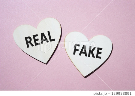 Real or Fake symbol. Concept word Real or Fake on wooden hearts. Beautiful pink background. Business and Real or Fake concept. Copy space 129958891