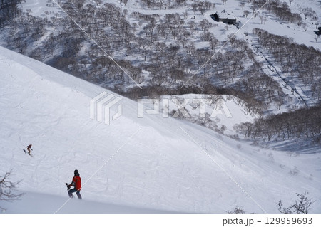 ニセコ東急 グラン・ヒラフ・ゲレンデのダイナミックコースからスキー場管理区域を滑るスキーヤー 129959693