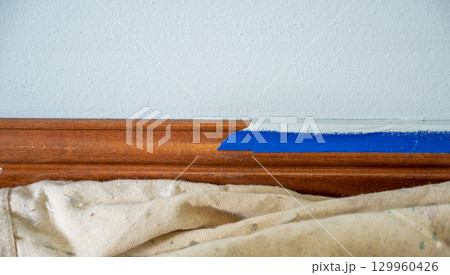 Interior painting project in a home with careful taping along the wooden trim in a light and airy room 129960426
