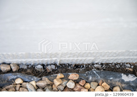 Construction work showing gravel and foundation wall with drainage layer for proper insulation and moisture control Construction work showing gravel and foundation wall with drainage layer for proper insulation and moisture control 129960439