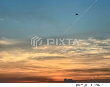夕焼け空を飛ぶ飛行機 129961502